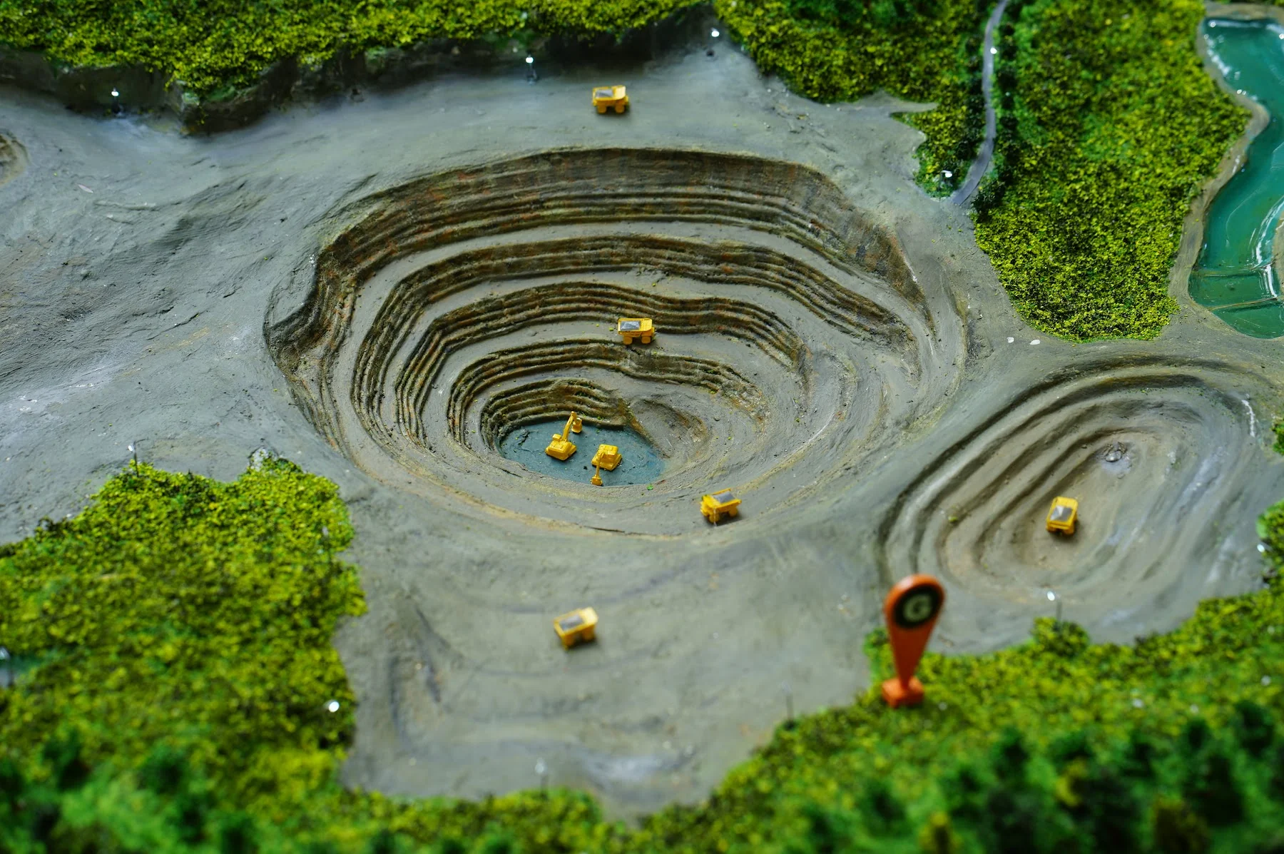 Close-up of Amman Mineral mining pit with stepped excavation and machinery.