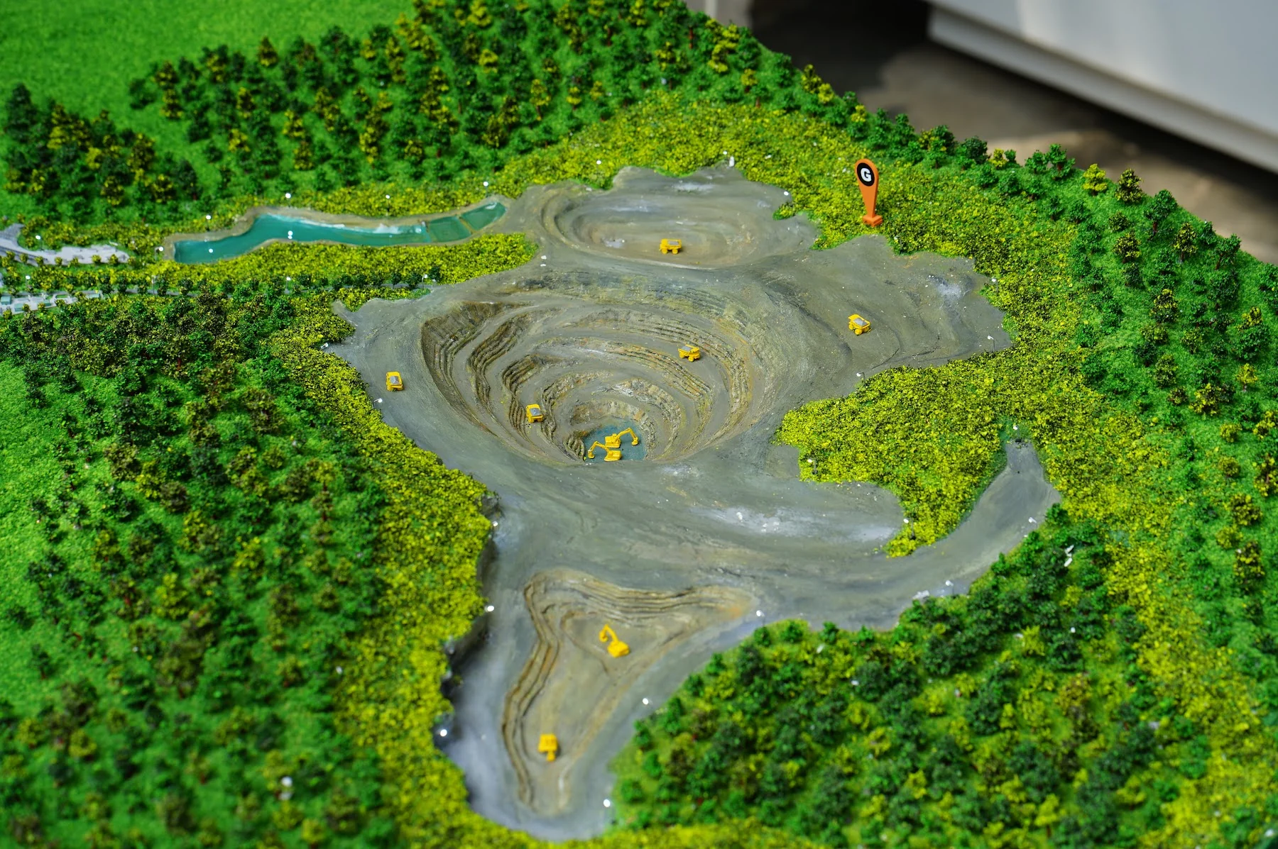 Amman Mineral mining pit diorama with forest context and haul roads.