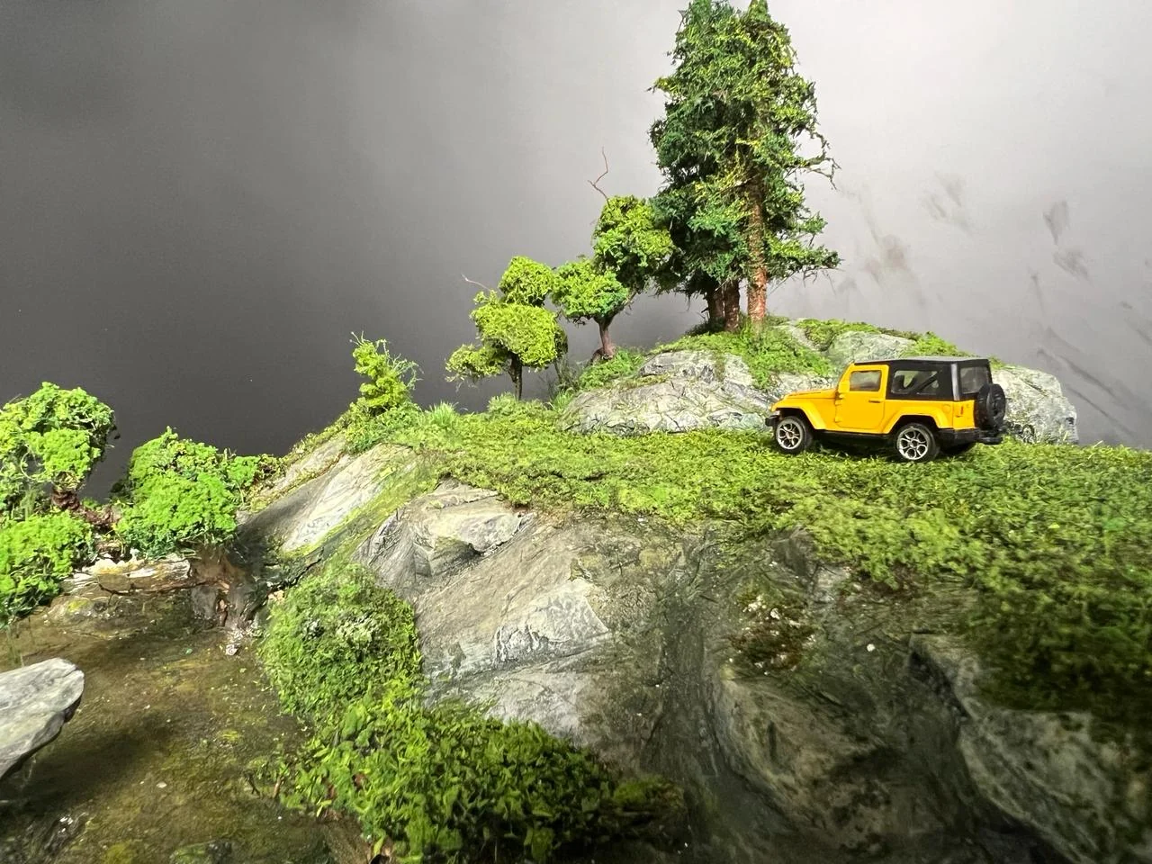Side view of miniature vehicle on a green rocky ridge.